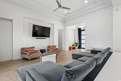 Living room featuring baseboards, a tray ceiling, ceiling fan, and wood finished floors