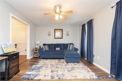 Living room featuring dark wood-style flooring and a ceiling fan