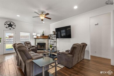 Living area with vaulted ceilings, a rustic wood mantel, and a modern ceiling fan.