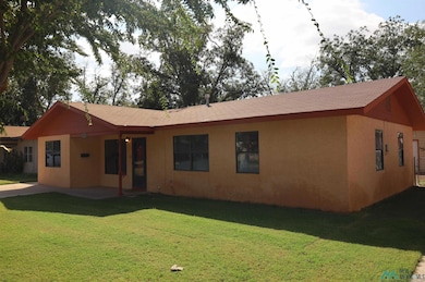 View of front of house featuring a front lawn, stucco siding, a shingled roof, and a patio area