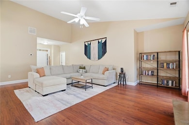 Living room with wood finished floors, ceiling fan, and high vaulted ceiling