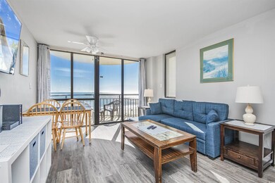 Living room featuring floor to ceiling windows, ceiling fan, wood finished floors, and a water view