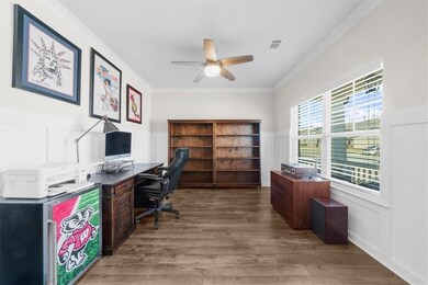 Office with a ceiling fan, a wainscoted wall, wood
