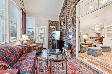 Living area with brick wall, high vaulted ceiling, and a chandelier