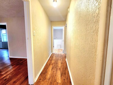 Corridor with a textured wall, hardwood / wood-style flooring, and a textured ceiling