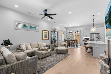 Living area with light wood finished floors, recessed lighting, ceiling fan, and a chandelier