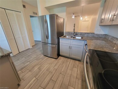 Kitchen with stainless steel appliances, light wood finished floors, ceiling fan, stone counters, and gray cabinets