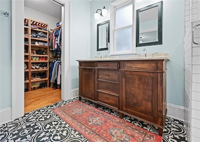 Bathroom featuring double vanity, a spacious closet, and wood finished floors
