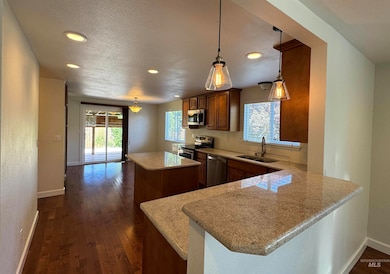 Kitchen with dark wood-style floors, healthy amount of natural light, a center island, a textured ceiling, and stainless steel appliances