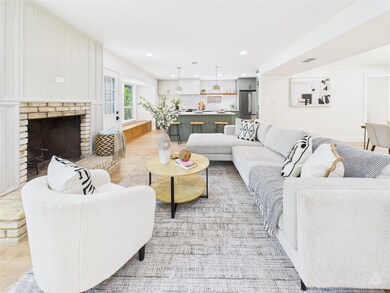 Living room featuring a brick fireplace, light wood-style floors, and recessed lighting
