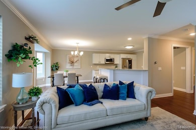 Living area featuring ornamental molding, a chandelier, dark wood-style floors, a ceiling fan, and recessed lighting