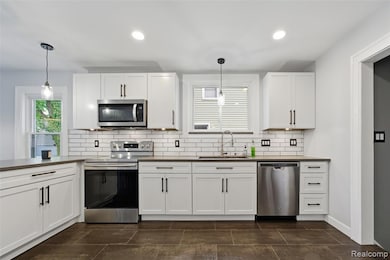 Kitchen with appliances with stainless steel finishes, white cabinetry, decorative light fixtures, recessed lighting, and decorative backsplash