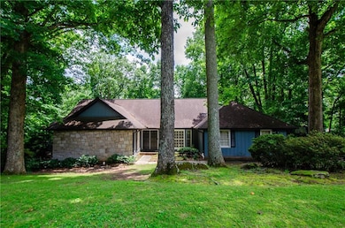 View of front of home featuring a front lawn, roof with shingles, and stone siding