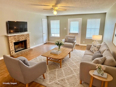 Living area with baseboards, ceiling fan, a brick