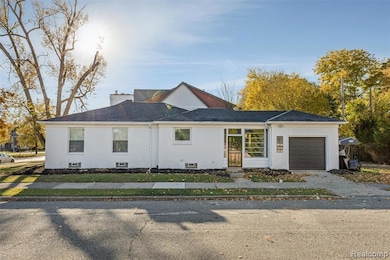 View of front facade featuring a garage, a chimney, roof with shingles, and brick siding