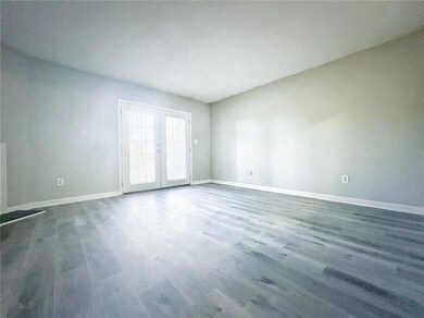 Empty room featuring baseboards, dark wood-style flooring, and french doors