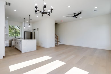 Unfurnished living room featuring a barn door, a chandelier, stairs, recessed lighting, and light wood-style floors