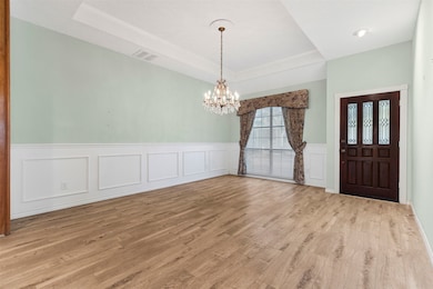 The dining room offers an elegant chandelier, wainscoting & a tray ceiling.