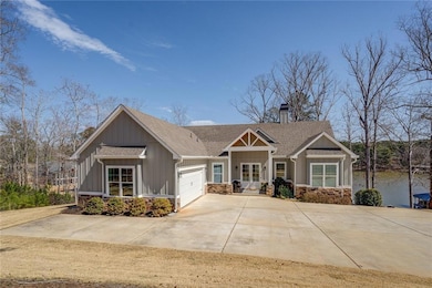 Craftsman inspired home with an attached garage, a chimney, driveway, french doors, and stone siding