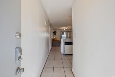 Hallway featuring light tile patterned flooring, rail lighting, and baseboards