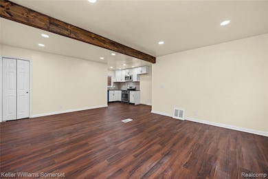 Unfurnished living room with recessed lighting, beam ceiling, and dark wood-style flooring