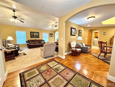 Living room featuring arched walkways, a textured ceiling, and light wood-type flooring