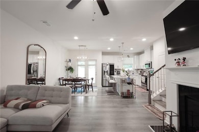 Living room featuring a ceiling fan, light wood finished floors, recessed lighting, and stairway