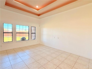 Spare room with light tile patterned floors, a tray ceiling, and ornamental molding