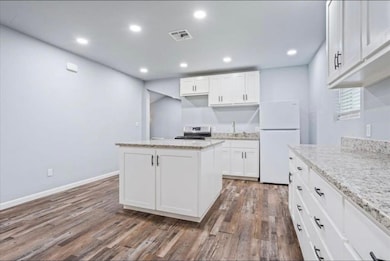 Kitchen featuring white cabinetry, freestanding refrigerator, dark wood-style flooring, recessed lighting, and a kitchen island
