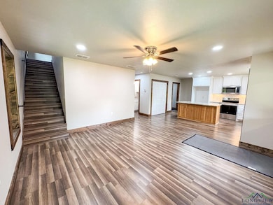 Unfurnished living room with wood finished floors, recessed lighting, a ceiling fan, and stairway
