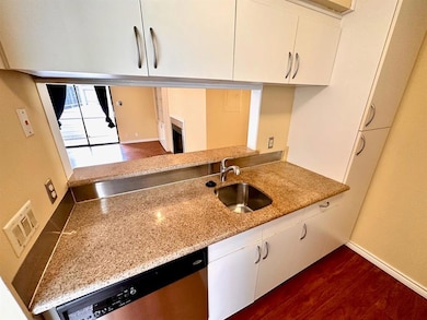 Kitchen featuring dishwasher, white cabinets, lig