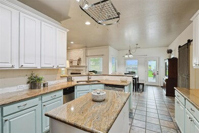 Kitchen featuring a center island, light tile floors, a barn door, sink, and dishwasher
