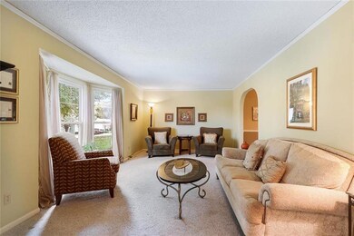 A large bay window overlooks the front yard and al