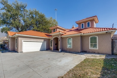 Mediterranean / spanish-style home with stucco siding, driveway, a garage, a chimney, and a tile roof