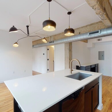 Kitchen featuring an island with sink, sink, light