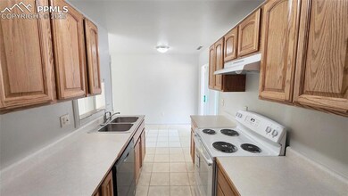 Kitchen with white range with electric stovetop, under cabinet range hood, a sink, dishwashing machine, and brown cabinets