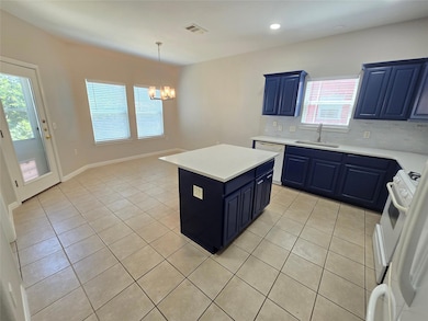 Kitchen with blue cabinets, light tile patterned flooring, backsplash, a center island, and recessed lighting