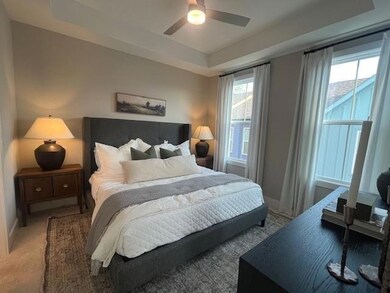 Bedroom featuring a tray ceiling, ceiling fan, and carpet floors