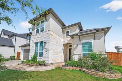 This modern two-story home features a stone and stucco exterior with a well-maintained front garden and driveway. It offers a sleek, contemporary design with ample windows and a welcoming entrance.