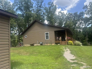 View of side of property featuring a lawn and a porch