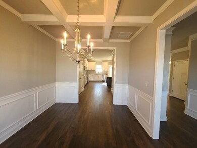 Unfurnished dining area featuring dark wood-style flooring, a chandelier, crown molding, beam ceiling, and coffered ceiling