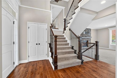 Stairs featuring wood-type flooring, a stone fireplace, and recessed lighting