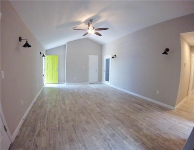 Unfurnished living room with a ceiling fan, vault