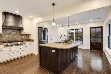 Kitchen with custom range hood, a sink, visible ve