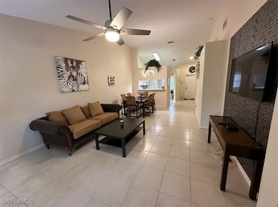 Living room featuring high vaulted ceiling, visible vents, baseboards, a ceiling fan, and light tile patterned floors