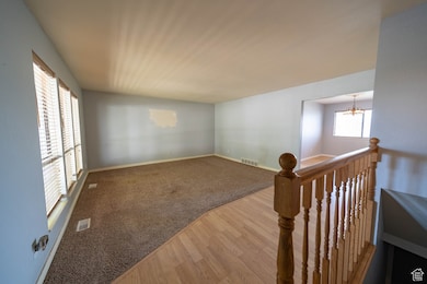 Spare room featuring a chandelier, wood finished floors, and carpet flooring