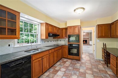 Kitchen featuring black appliances, a sink, under cabinet range hood, glass insert cabinets, and dark stone counters