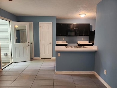 Kitchen featuring black microwave, a sink, light c