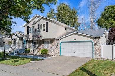 View of front of house featuring stone siding, a garage, driveway, and stucco siding
