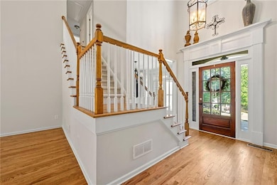 Entryway with wood finished floors, baseboards, a high ceiling, and stairs